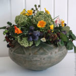 Blumenvase gefüllt mit herbstlichen Blumen und Früchten